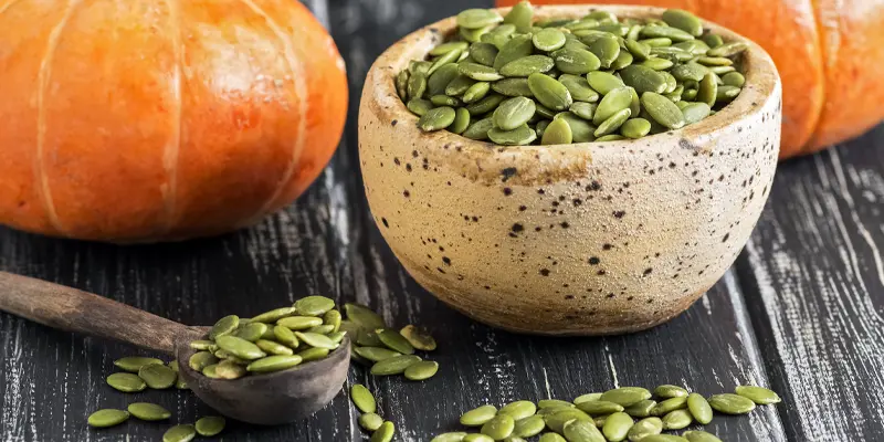 Pumpkin seeds with pumpkin in the background