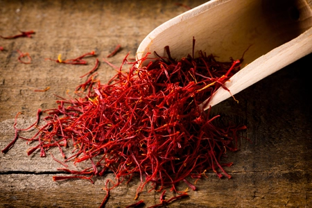 saffron threads with spice shovel on wooden background