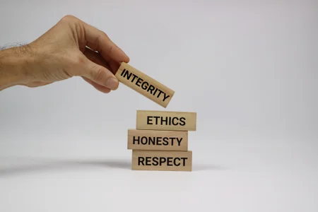 Hand Arranging Wooden Blocks with Ethics, Honesty, and Integrity Texts.